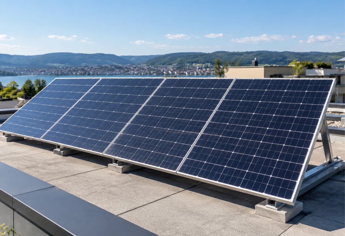 Vier aufgeständerte Solarmodule auf einem Flachdach mit Blick auf einen See und bewaldete Hügel im Hintergrund.