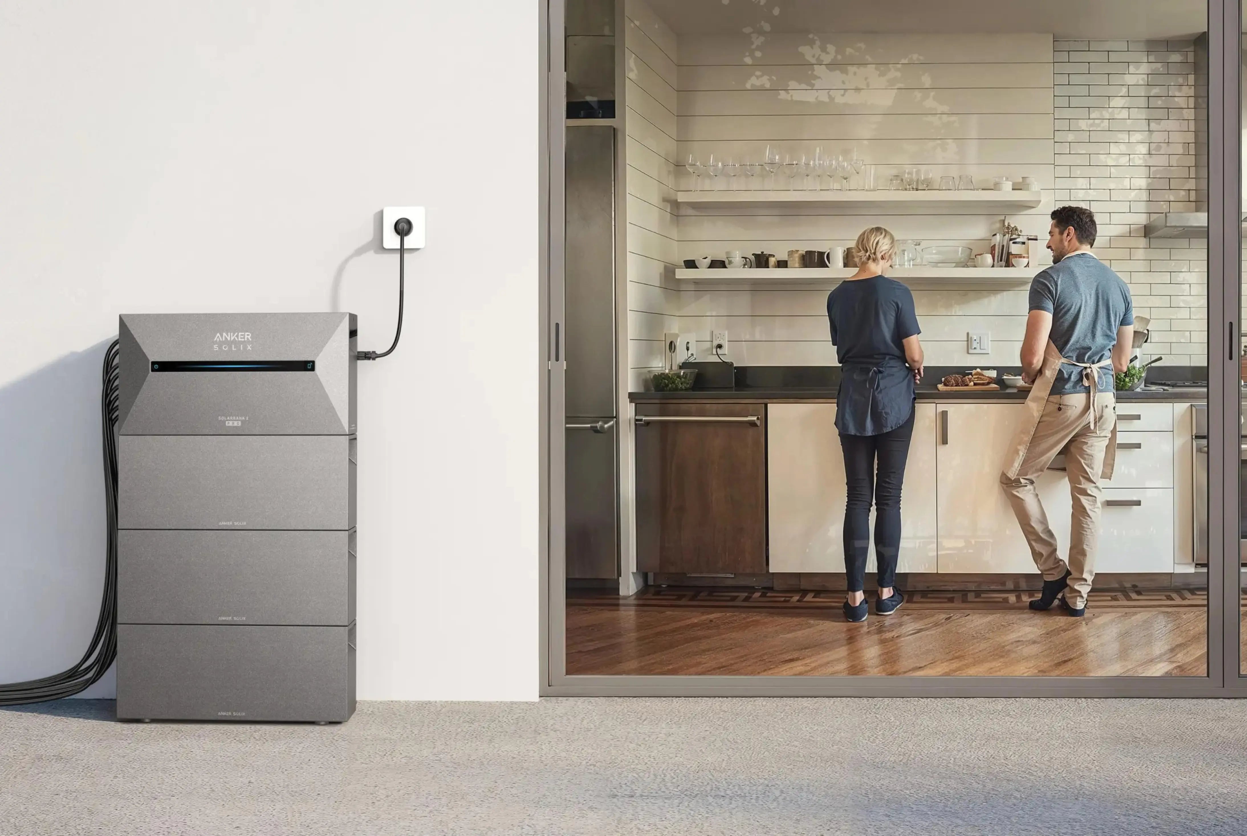 Zwei Personen kochen in der Küche, Balkonkraftwerk mit erweitertem Stromspeicher auf dem Balkon im Hintergrund.