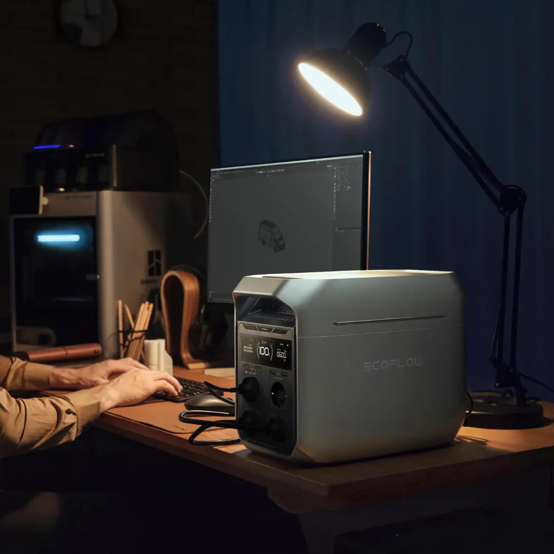 EcoFlow Delta 3 Pro Powerstation auf Schreibtisch. Nebendran sitzt eine Person am Computer und eine Lampe leuchtet.