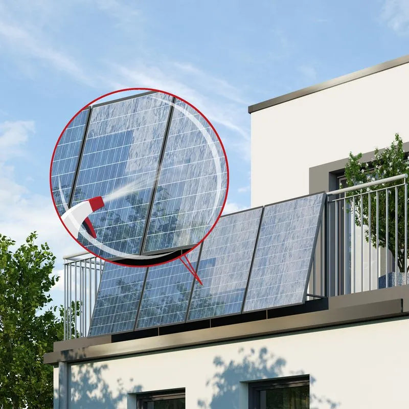 Balkonkraftwerk montiert an Balkon eines modernen Hauses. Hingezoomt zum Bereich des Solarmoduls, Sprühflasche sprüht Balkonkraftwerk-Reiniger auf das Modul.