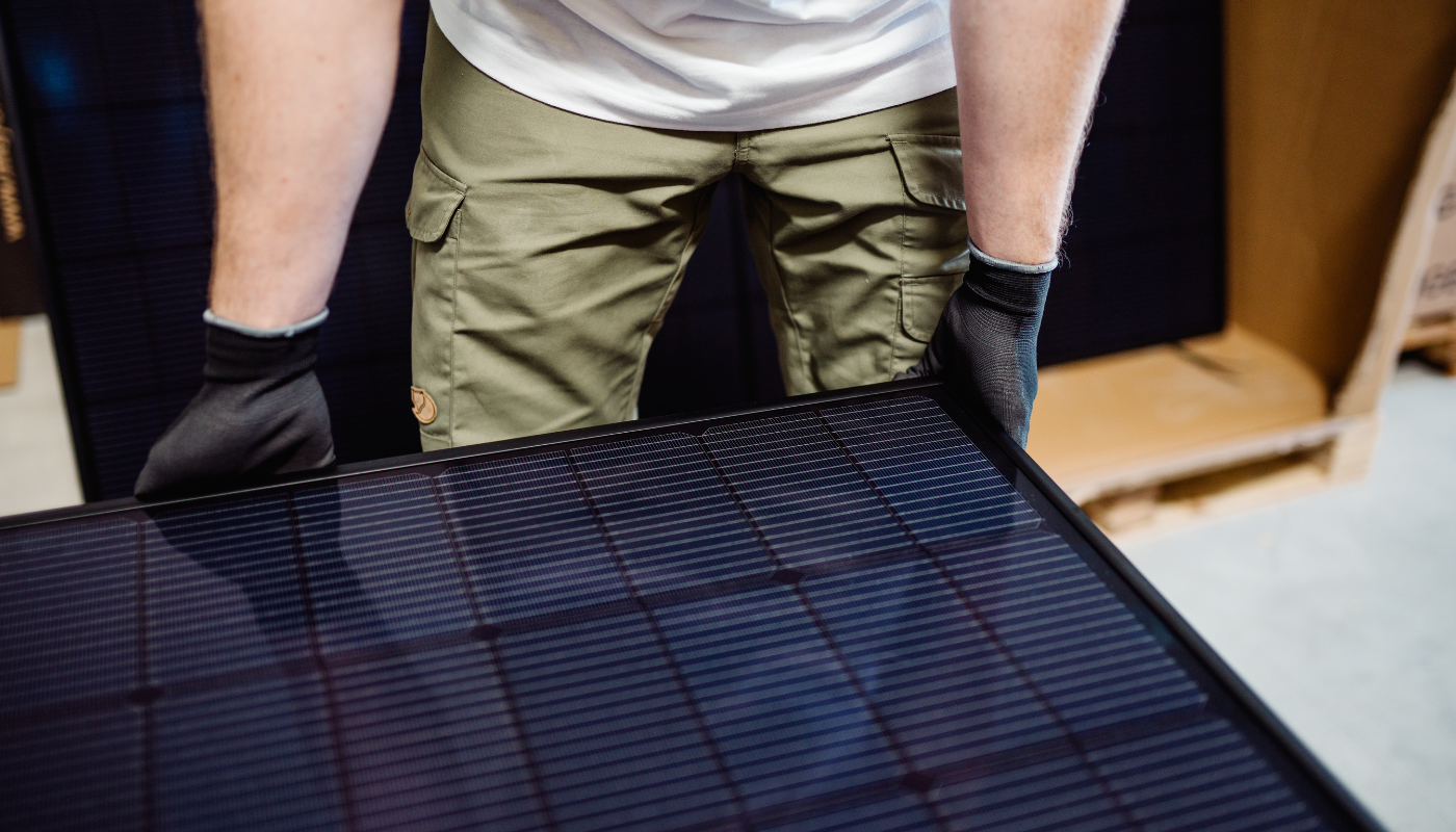 Meyer Burger Black Solarmodul wird von Mann angehoben als Bestandteil der Balkonstrom Premium Balkonkraftwerke