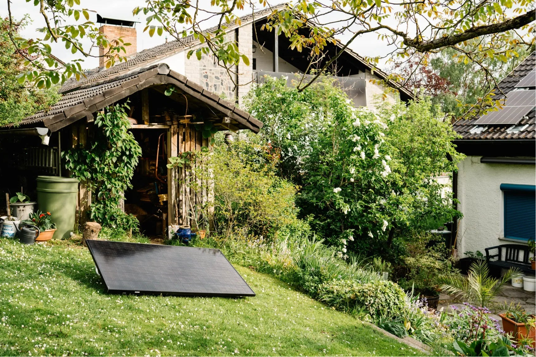 Solarmodul auf Gartenfläche mit Gartenhaus und Haus im Hintergrund