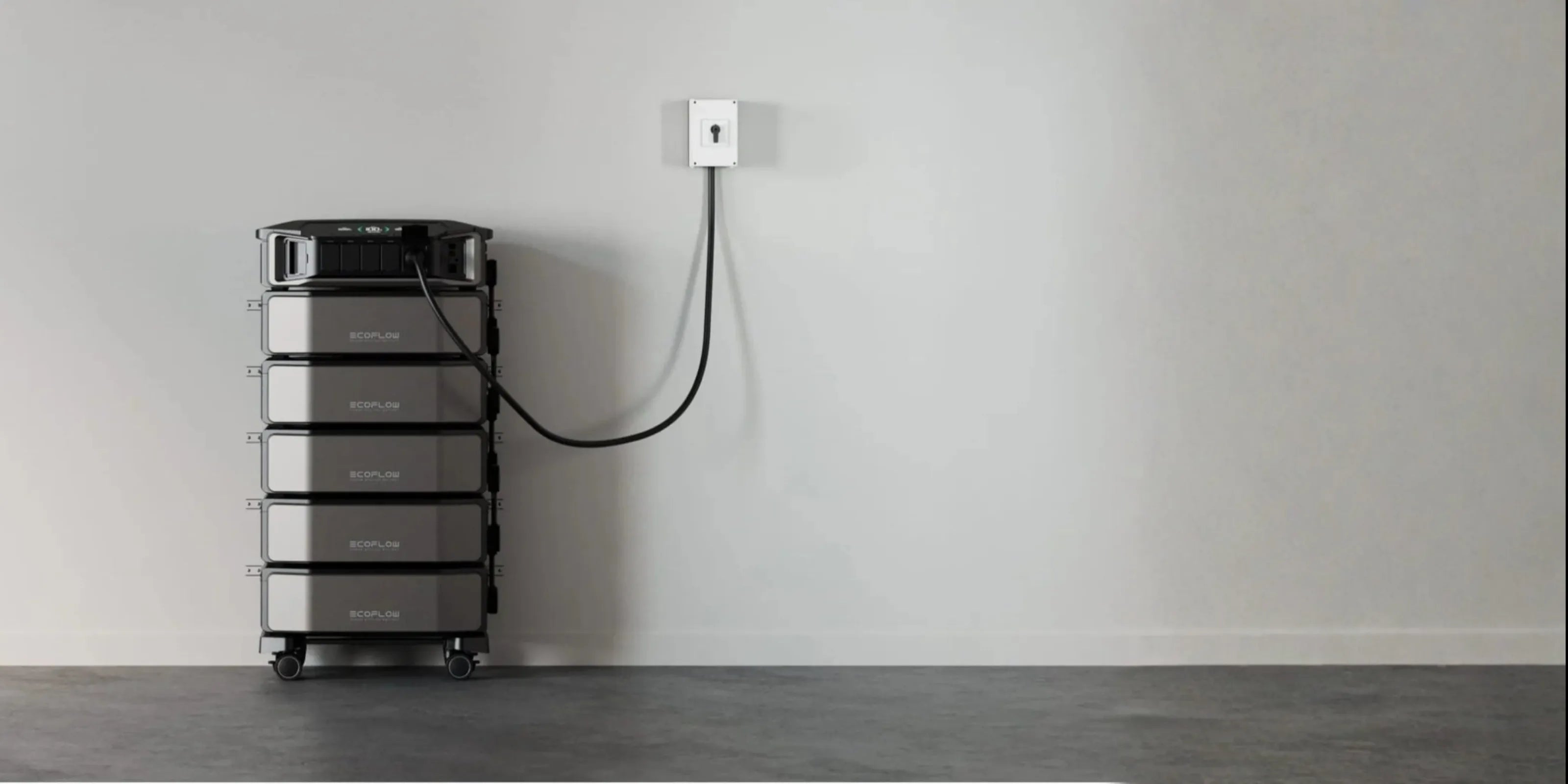 EcoFlow DELTA Pro Ultra mit 4 Zusatzbatterien vor einer weißen Wand, angeschlossen an einer Steckdose